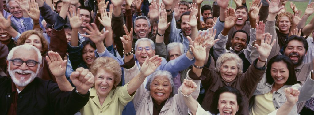 group of people with their hands raised smiling at the camera